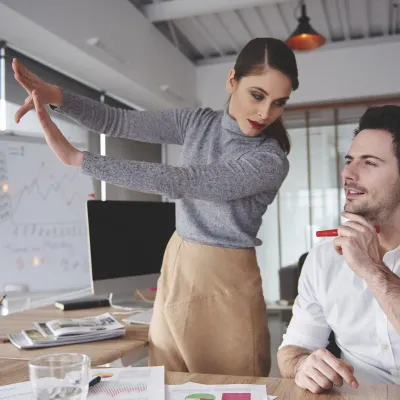 Dos personas de un equipo de agencia revisando una estrategia frente a una pizarra