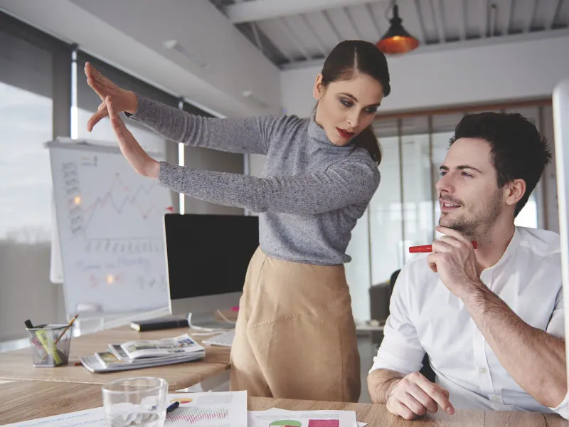 Dos personas de un equipo de agencia revisando una estrategia frente a una pizarra